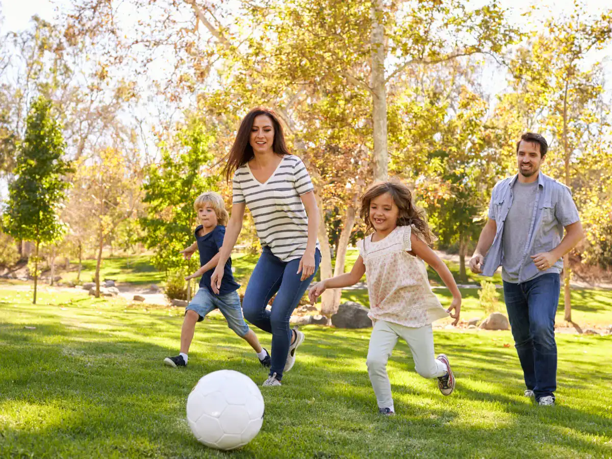 Family enjoying outdoor soccer in a scenic western landscape park.