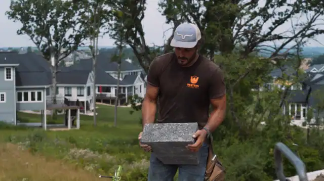 Man installing stone pavers for hardscaping project in Madison, WI.